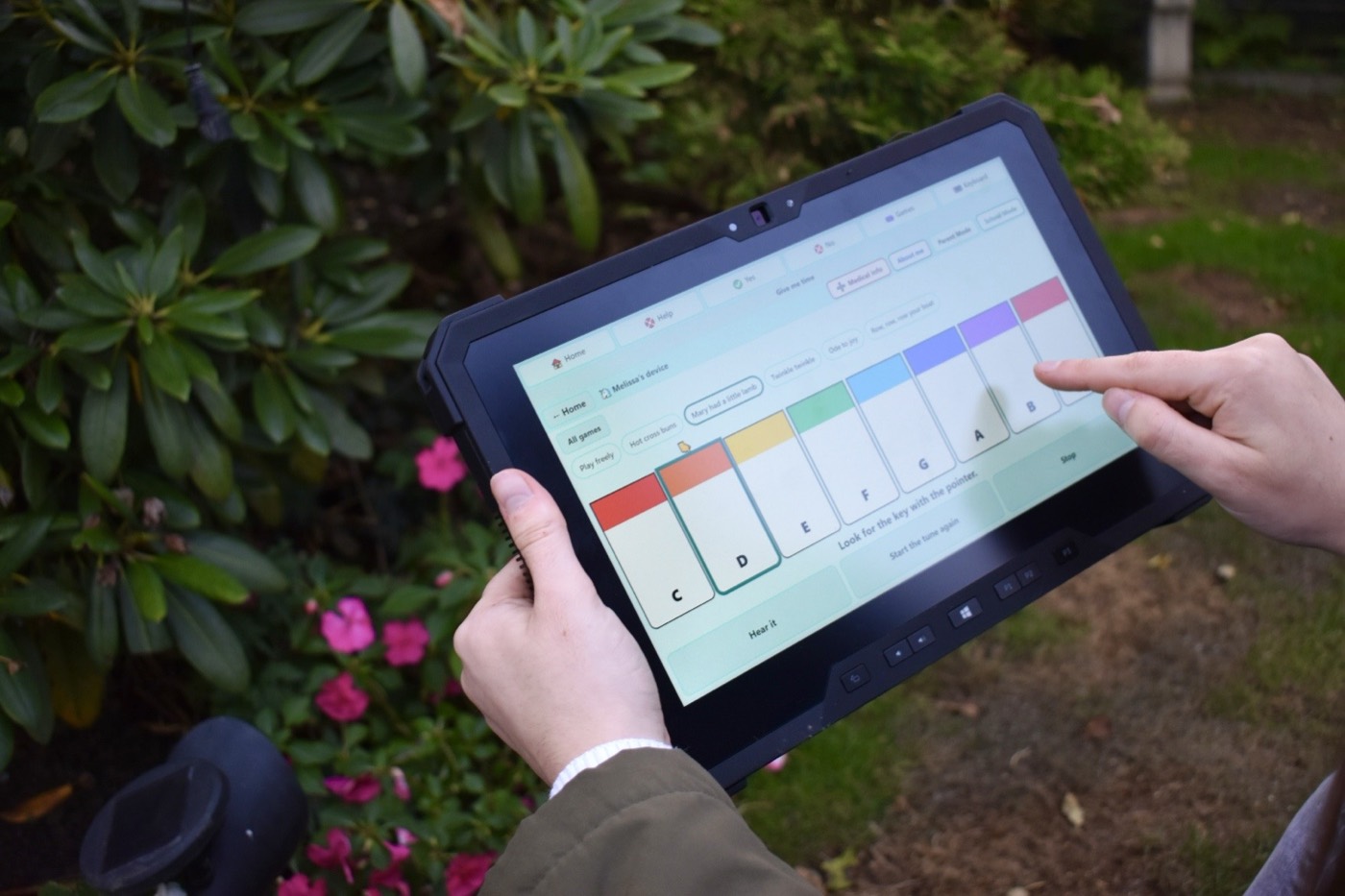 Playing the Piano game on the tablet in the garden, pressing a coloured key